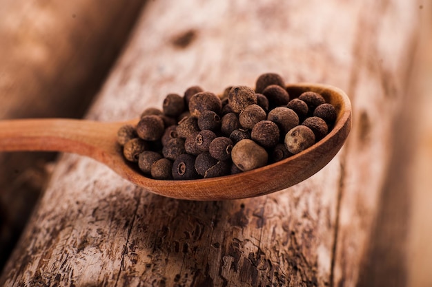 Cucchiaio di legno con pimento integrale Pepe nero grande in un piatto su una superficie vintage