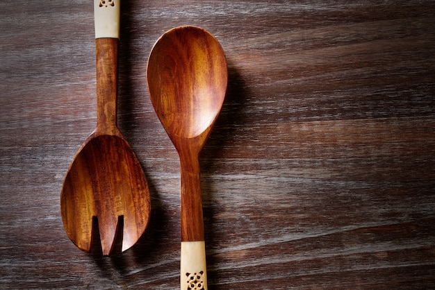 cucchiaio di legno e forchetta sul bordo di legno