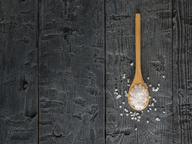 Cucchiaio di legno riempito con sale marino grosso su un tavolo di legno. La vista dall'alto. Lay piatto.