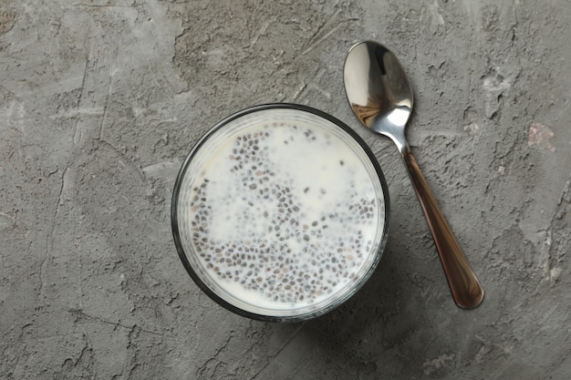 Cucchiaio e bicchiere con budino di chia su grigio