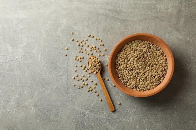 Cucchiaio e ciotola con legumi su grigio