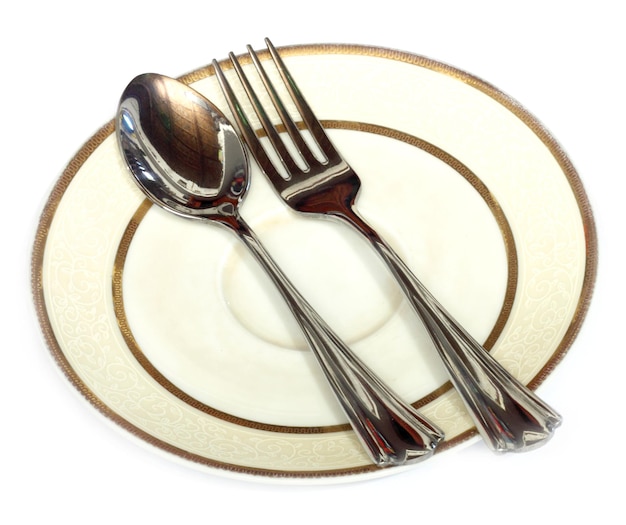 Cucchiaio e forchetta in un piatto su bianco