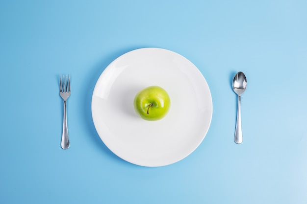 cucchiaio e forchetta, mela verde sul piatto in ceramica bianca