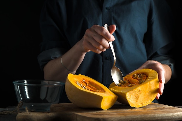 Cucchiaio in mano metà zucca su un tavolo su sfondo blu