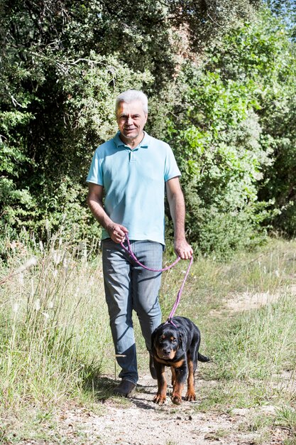 Cucciolo di rottweiler e proprietario nella natura in autunno