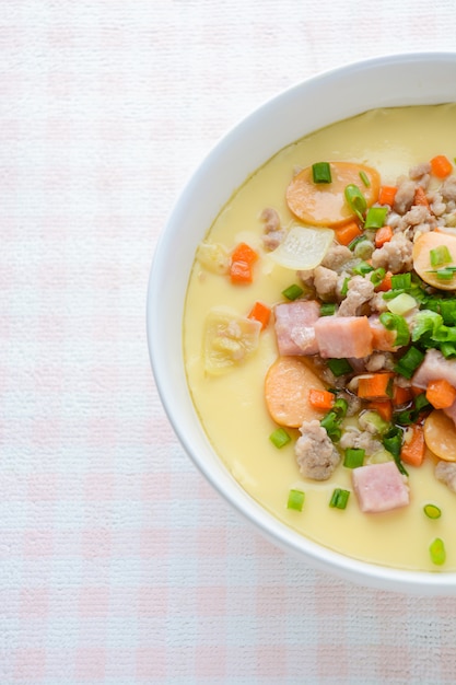 Cucina al vapore con crema pasticcera all'uovo in una ciotola bianca con carne di maiale, salsiccia e pancetta tritate