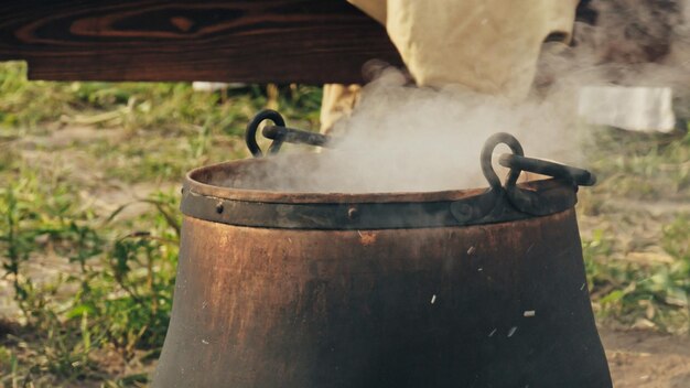 Cucina all'aperto, cucina sul rogo, calderone di metallo sul fuoco, primo piano. Ricostruzione storica del XIV-XV secolo, Fiandre.