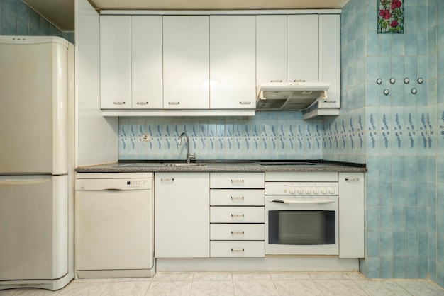 Cucina con armadi in legno bianco elettrodomestici da incasso controsoffitti in granito rosa e piastrelle blu sulle pareti