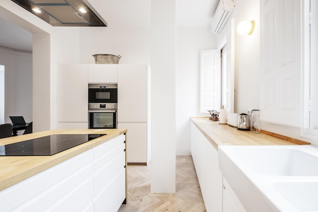 Cucina dal design contemporaneo con armadi senza maniglie isola centrale con cassetti bianchi controsoffitti in legno e finestre con persiane in legno bianco