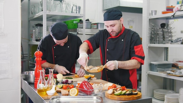 Cucina del ristorante due uomini che lavorano per servire i piatti un uomo con in mano un pesce