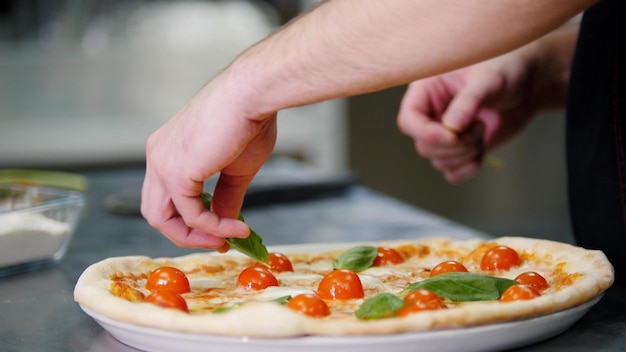 Cucina del ristorante uno chef che decora la pizza con il verde