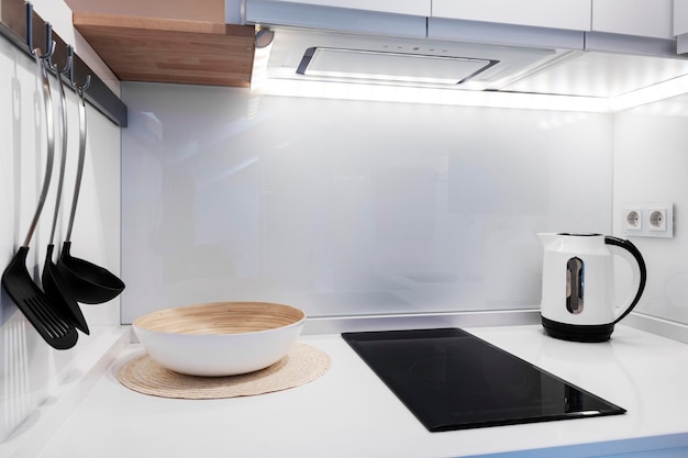 Cucina di design con morbide linee bianche elettrodomestici integrati e mobili laccati bianchi Tavolo da pranzo in legno Maiza e pavimenti in gres abbinati TV e parete e piante decorative