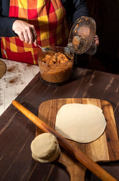 Cucina e concetto di casa. Donna che prepara torte fatte in casa con ripieno di carne tritata sul tavolo della cucina a casa