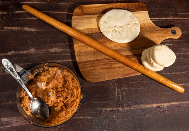 Cucina e concetto di casa. Preparazione di torte fatte in casa con ripieno di carne macinata sul tavolo della cucina a casa