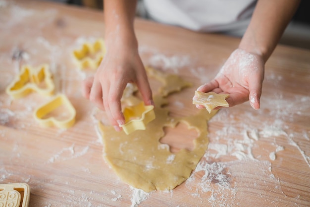 Cucina e concetto di casa - primo piano delle mani del bambino che preparano biscotti di pasta fresca a casa.