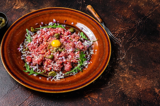 Cucina francese Tartare di manzo con tuorlo d'uovo crudo. Sfondo scuro. Vista dall'alto. Copia spazio.