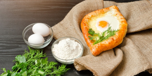 Cucina georgiana. Khachapuri su tela di sacco, farina, uova. Tavolo nero.