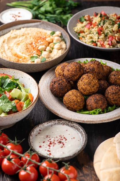 Cucina mediorientale o araba falafel hummus tabouleh pita e verdure su fondo di legno fuoco selettivo