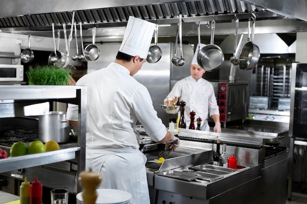 Cucina moderna. Gli chef preparano i piatti sui fornelli nella cucina di un ristorante o di un hotel.