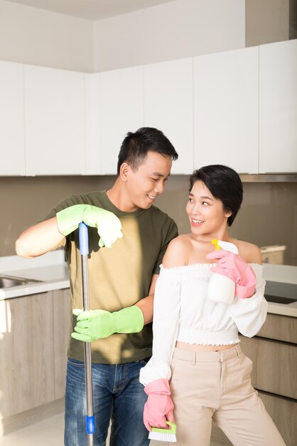 Cucina moderna sorridente giovane donna asiatica e uomo che puliscono il pavimento a casa