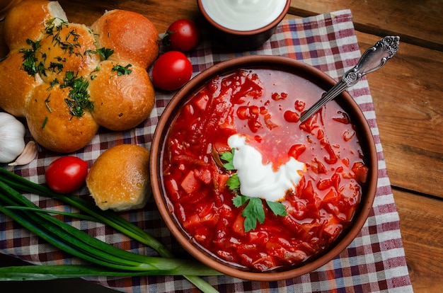 Cucina nazionale ucraina - borsch rosso con ciambelle in una ciotola di argilla su un tavolo di legno.