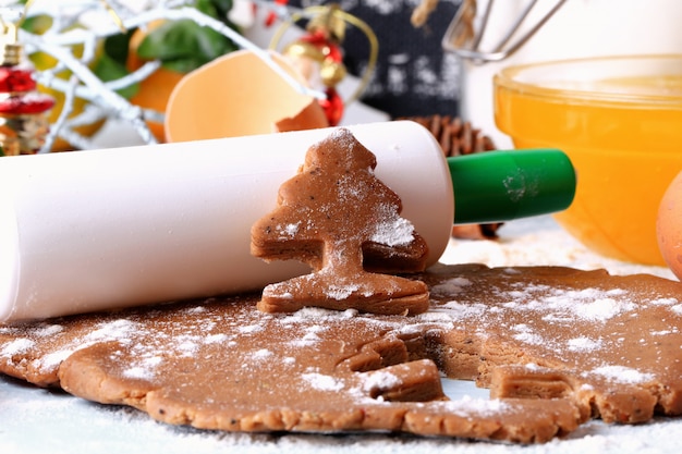 Cucinando i biscotti dello zenzero per i dolci casalinghi di Natale su uno stile rustico del fuoco molle selettivo del fondo di legno leggero