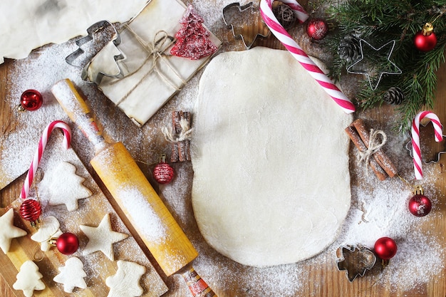 Cucinare biscotti al burro di forme diverse su un tavolo di legno con accessori natalizi