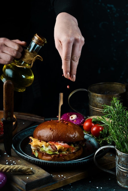 Cucinare Burger con pancetta e gamberetti nelle mani di uno chef su sfondo scuro