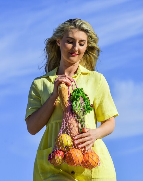 Cucinare cibi sani. la donna porta l'insalata di mele e arance e il pane in un sacchetto di corda. la ragazza va a fare shopping. goditi il clima estivo. uno stile di vita sano. cura la tua salute. fitness e dieta. solo cibo biologico.