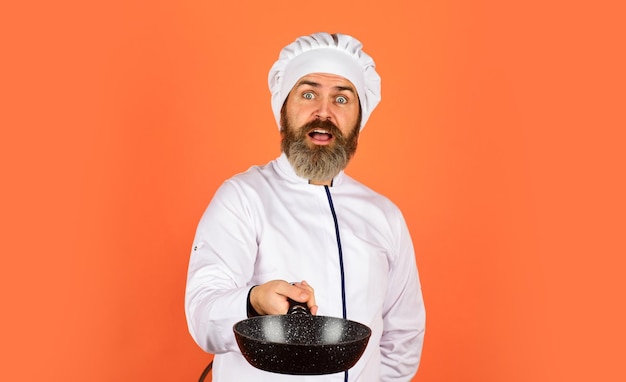 Cucinare come un professionista Cucina regolare Pasto facile e gustoso preparato a casa Colazione fatta in casa Preparare il cibo in cucina Cucinare il concetto di cibo Padella di alta qualità Uomo barbuto cuoco uniforme bianca