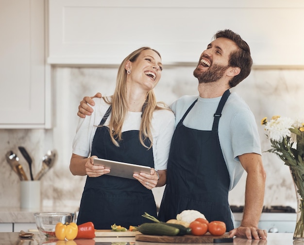 Cucinare divertente o felice coppia con tablet o cibo per una dieta vegana sana insieme a casa Sorridere ridere o donna in cucina per abbracciare o legare con l'amore o uomo imparare una ricetta per la cena sul blog online