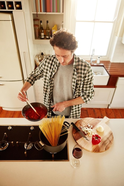 Cucinare gli spaghetti o sopra dell'uomo in cucina con una sana dieta vegana per l'alimentazione o le verdure a casa in Australia Bicchiere da vino cibo o persona di sesso maschile nella cucina di casa in preparazione per la cena