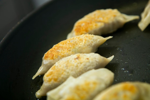 Cucinare i gyoza giapponesi. Tradizionali gnocchi giapponesi ripieni di carne e verdure.