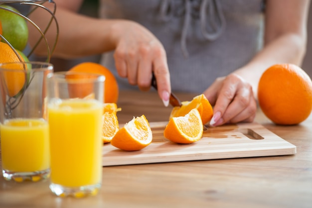 Cucinare il cibo e il concetto di vigore del veganismo e mangiare sano primo piano della mano femminile che taglia l'arancia a fette