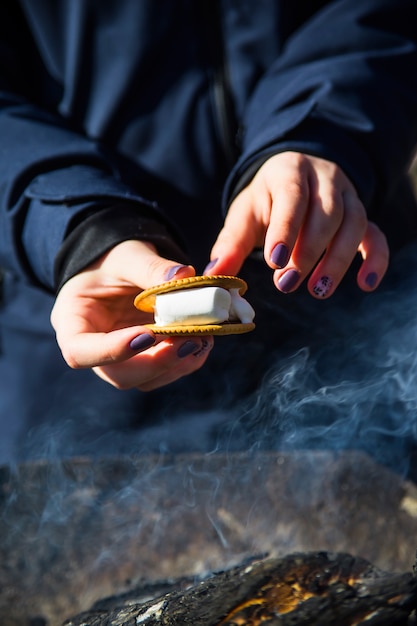 Cucinare il dessert con marshmallow dal fuoco in un pic-nic in natura