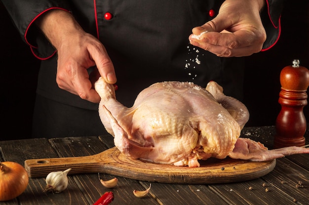 Cucinare il pollo in cucina con le mani di un cuoco