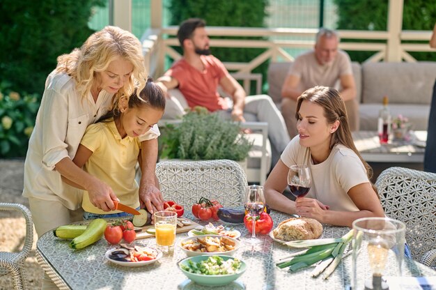 Cucinare insieme. Donne che tagliano le verdure per il commensale e sembrano coinvolte