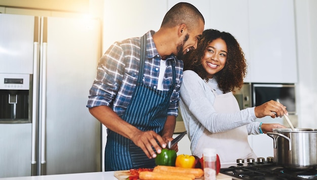 Cucinare insieme per rendere il cibo migliore Inquadratura di una giovane coppia che cucina insieme a casa