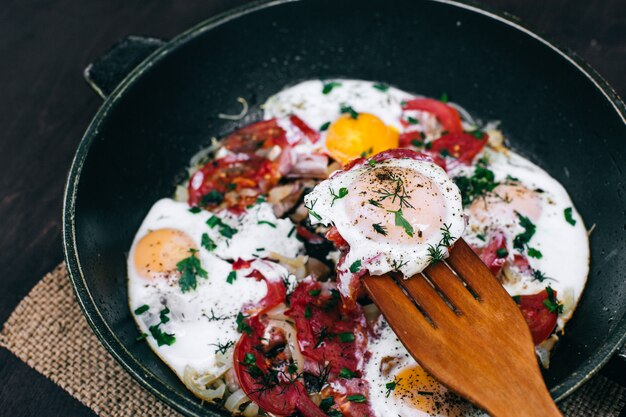 Cucinare la cena nella cucina di casa. Deliziose uova strapazzate con pomodori e cipolle