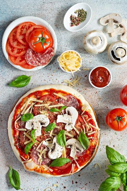 Cucinare la pizza italiana con pomodoro, formaggio, salame di funghi e basilico