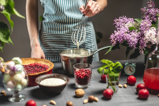 Cucinare la torta di mirtilli fatta in casa. Un pasticcere femminile sta montando una frusta di panna acida