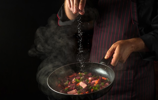 Cucinare le verdure fresche Lo chef aggiunge il sale a una padella fumante Grande cuisine