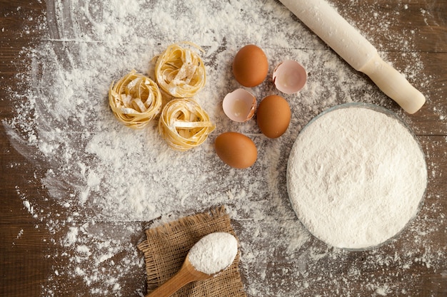 Cucinare qualcosa di delizioso con uova, farina e fettuccine con l'aiuto delle stoviglie. Vista dall'alto.