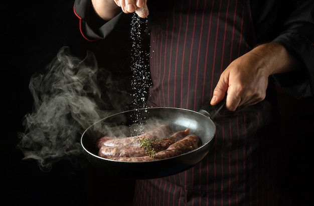 Cucinare salsicce di carne in padella Lo chef aggiunge sale a una padella calda Spazio libero per la pubblicità