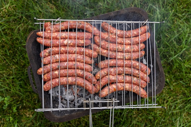 Cucinare salsicce sulla griglia a carbone all'aperto Italia Tradizionale barbecue con macine all'aperto