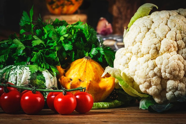 Cucinare sfondo autunno cibo pomodori zucche cavolfiore erbe e spezie su legno rustico tavolo da cucina con padella in ghisa macinini per spezie tagliere spezie e condimenti barattoli di conservazione