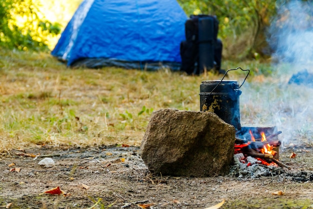 Cucinare sul fuoco in campeggio Tenda e zaino sullo sfondo