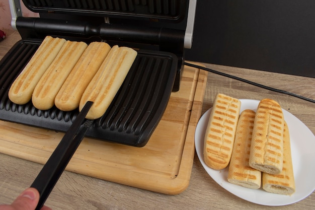 Cucinare un hot dog a casa sulla griglia, l'intero processo dalla tostatura del pane alla piegatura di un hot dog in un unico pezzo