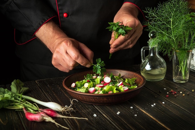 Cucinare un'insalata di verdure fresche con le mani di uno chef in cucina Cucina vegetariana