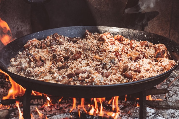 Cucinare una paella di riso, pollo, carciofi, salsicce, cibo tipico spagnolo